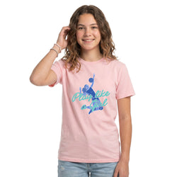 A young woman with wavy brown hair smiling, wearing a light pink crewneck t-shirt with a blue graphic of a volleyball player and the text 'Play like a girl'.