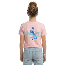 A woman viewed from behind wearing a light pink t-shirt with a blue graphic of a volleyball player and the text 'Play like a girl' on the back, paired with light wash blue jeans against a plain white background.