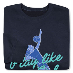 A folded navy blue crewneck sweatshirt featuring a graphic of a volleyball player in blue and teal text that reads 'play like a girl'.