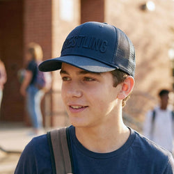 Young boy wearing a navy'Wrestling' cap outdoors