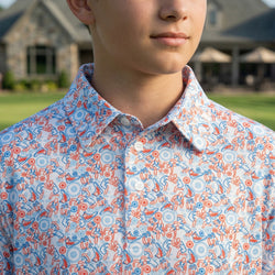 Person wearing a wrestling patterned polo shirt outdoors with a blurred background