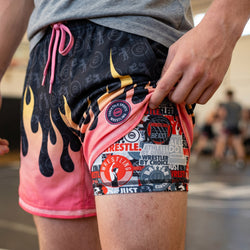 Person wearing colorful wrestling shorts with graphic designs and text.