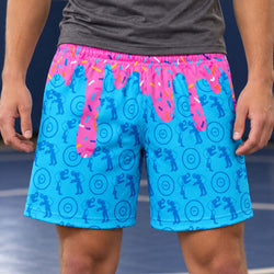 Teen wearing blue wrestling pattern shorts with ice cream drip indoors in a wrestling mat.